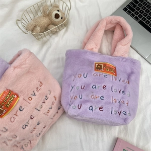 Détail d'un sac cabas en peluche douce avec broderie 'you are loved' et patch d'ours