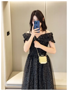 Detailed view of a gold geometric 3D chain box bag paired with a black sequin dress
