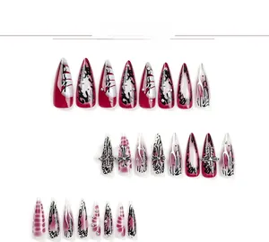 Detail of stiletto press-on nails with silver metallic crosses and red graffiti art