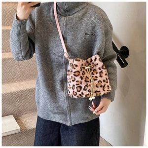 Detail of leopard print plush bucket bag with chain strap on a model side view