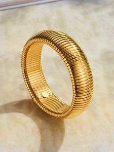 Detailed view of wide gold titanium steel bangle with vertical textured ridges