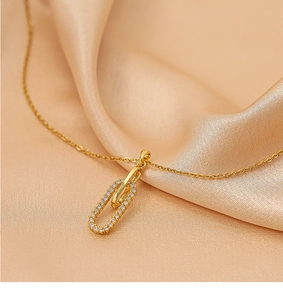 Gros plan d'un pendentif trombone doré avec zircons sur un tissu en satin de champagne