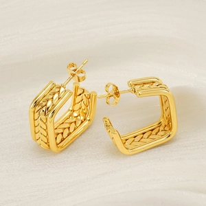 Élégantes boucles d'oreilles carrées dorées avec texture tressée sur satin blanc