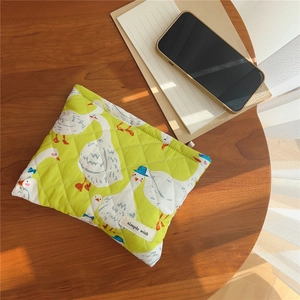 Quilted fabric pouch with green duck print on wood table next to phone and notebook