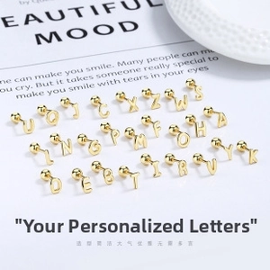 Flat lay of 26 gold S925 sterling silver alphabet stud earrings with screw-back design