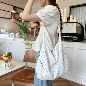 Lifestyle shot of large capacity canvas tote bag with black polka dots in a cozy cafe