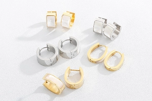 Flat lay of gold and silver shell earrings with mother of pearl inlay on white background