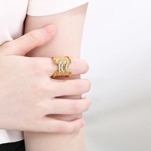 Detailed close-up of a wide 18K gold-plated ring with pavé rhinestones in a knot design