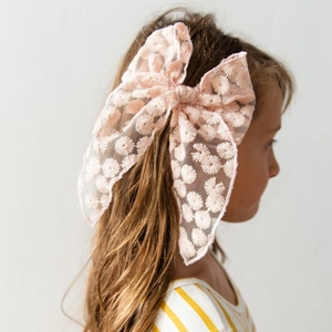 Detail of pink embroidered lace bow hair clip worn by a young girl for hair styling