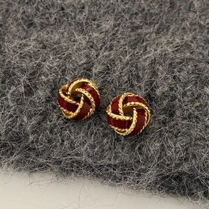 Macro view of French vintage knot stud earrings with red enamel and golden rope texture