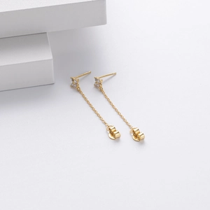 Close-up of gold flower earrings with pavé zircons and long tassels on white stones