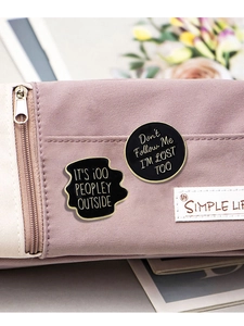 Detail of funny quote enamel pins with gold edges pinned on a purple canvas bag