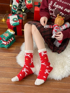Detail of plush Christmas socks with reindeer patterns and fuzzy white trim on a festive rug