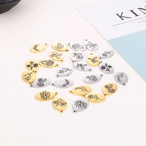 Vue détaillée de pendentifs ovales en acier inoxydable avec fleurs de naissance en or et argent
