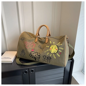 Macro view of olive green canvas travel bag with colorful graffiti art and shoulder strap