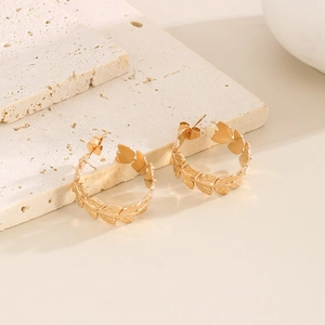 Detail of gold leaf pattern on stainless steel C-shaped hoop earrings with metal texture