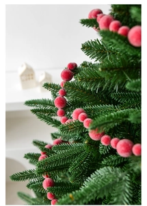 Macro view of frosted red berries on artificial Christmas tree branches with snow effect