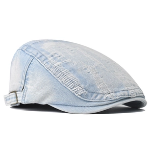 Detail of light blue distressed denim cap with vintage rips and bronze metal buckle