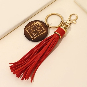 Detailed macro view of wood MAMA pendant with red tassel and golden metal keychain