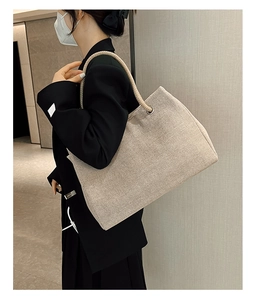 Detail of canvas straw tote bag with thick rope handles and braided texture on model