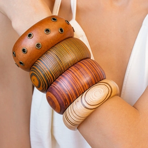 Detailed view of wide wooden bangles with rivet metal studs and spiral grain on a model