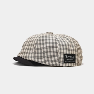 Detail of checkered newsboy cap featuring style fashionable patch and solid black brim