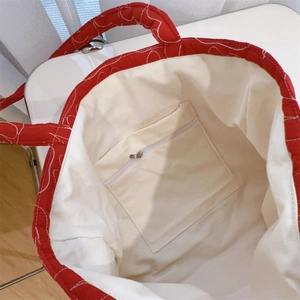 Detail view of the red canvas tote bag interior with beige lining and zip pocket
