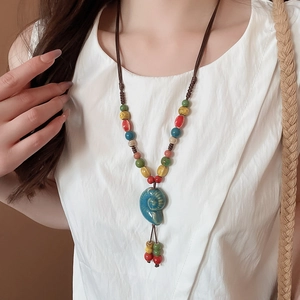 Dettaglio di un ciondolo a conchiglia in ceramica blu su una collana in corda intrecciata