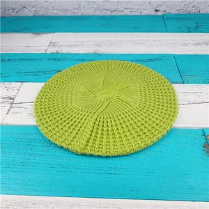 Detailansicht einer grasgrünen Strickbaske mit grober Spiralstruktur auf Holz