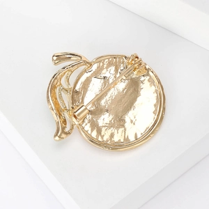 Golden enamel lemon brooch back view showing secure pin clasp on minimalist white stand