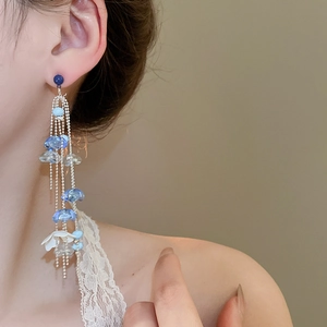 Detail of silver needle flower tassel earrings with blue beads on a female model