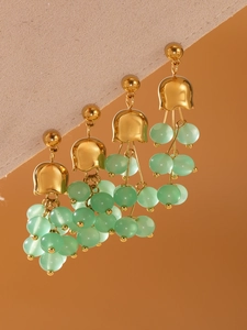 Dettaglio di orecchini mughetto con accenti dorati e nappe di perle verde menta
