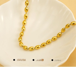 Macro shot of a gold beaded necklace made of stainless steel on a white shell tray
