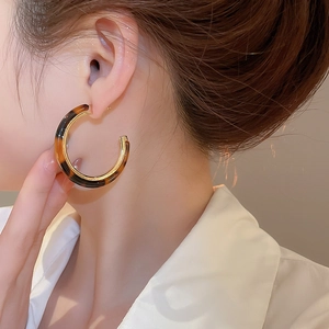 Macro view of vintage tortoiseshell resin C-shaped hoop earring on model side profile
