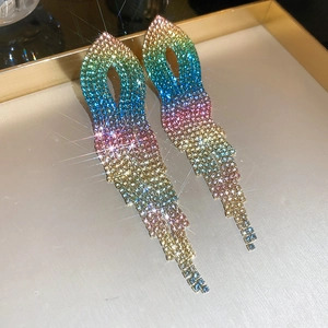 Detailed macro view of colorful gradient tassel earrings with rhinestones on golden tray