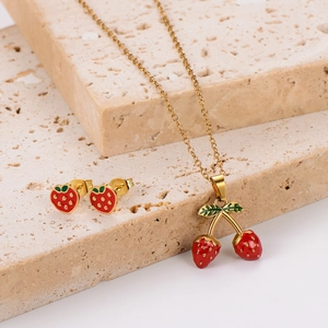 Elegant gold strawberry jewelry set with red enamel necklace and earrings on stone