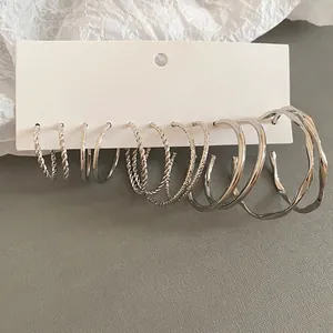 6 pairs of silver hoop earrings set with twisted, smooth, and wavy designs on display