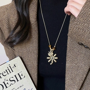 Detail of tiger eye beads and gold textured floral pendant on long chain necklace