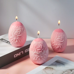 Detalle de velas rosas en forma de huevo con relieves de rosas y lazos en entorno hogareño