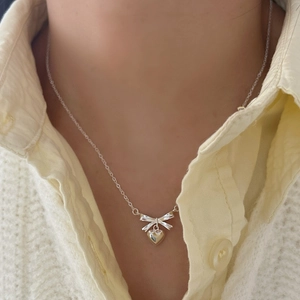 Elegant 925 sterling silver necklace featuring a bow and heart pendant on a woman neck