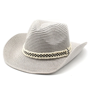 Dettaglio macro di un cappello di paglia grigio con fascia decorativa a scacchi b/n
