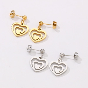 Detailed view of layered heart stud earrings in polished gold and silver finishes