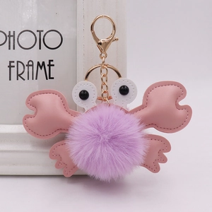 Detail of cute plush crab keychain with purple faux fur ball and pink faux leather legs