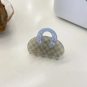 Top view of a handbag-shaped acetate hair claw with yellow and green checkerboard pattern
