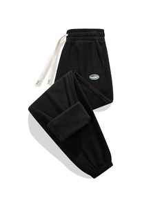 Dettaglio dei pantaloni in pile nero con coulisse elastica e patch del marchio applicata