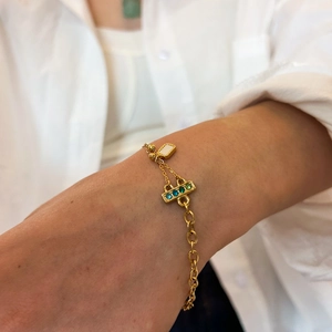 Close-up of gold titanium bracelet with white and turquoise stone charms on model