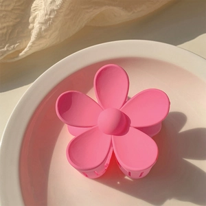 Detailed view of pink flower hair claw clip on a white ceramic plate for girls