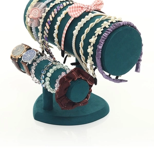 Close-up of dark green velvet double-tier jewelry stand displaying headbands and bracelets
