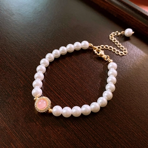 Détail macro du bracelet en perles dorées avec pierre rose et halo de zircons