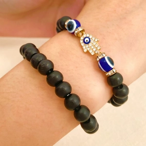 Close-up of black beaded bracelets with Hamsa Hand and Evil Eye charms on wrist